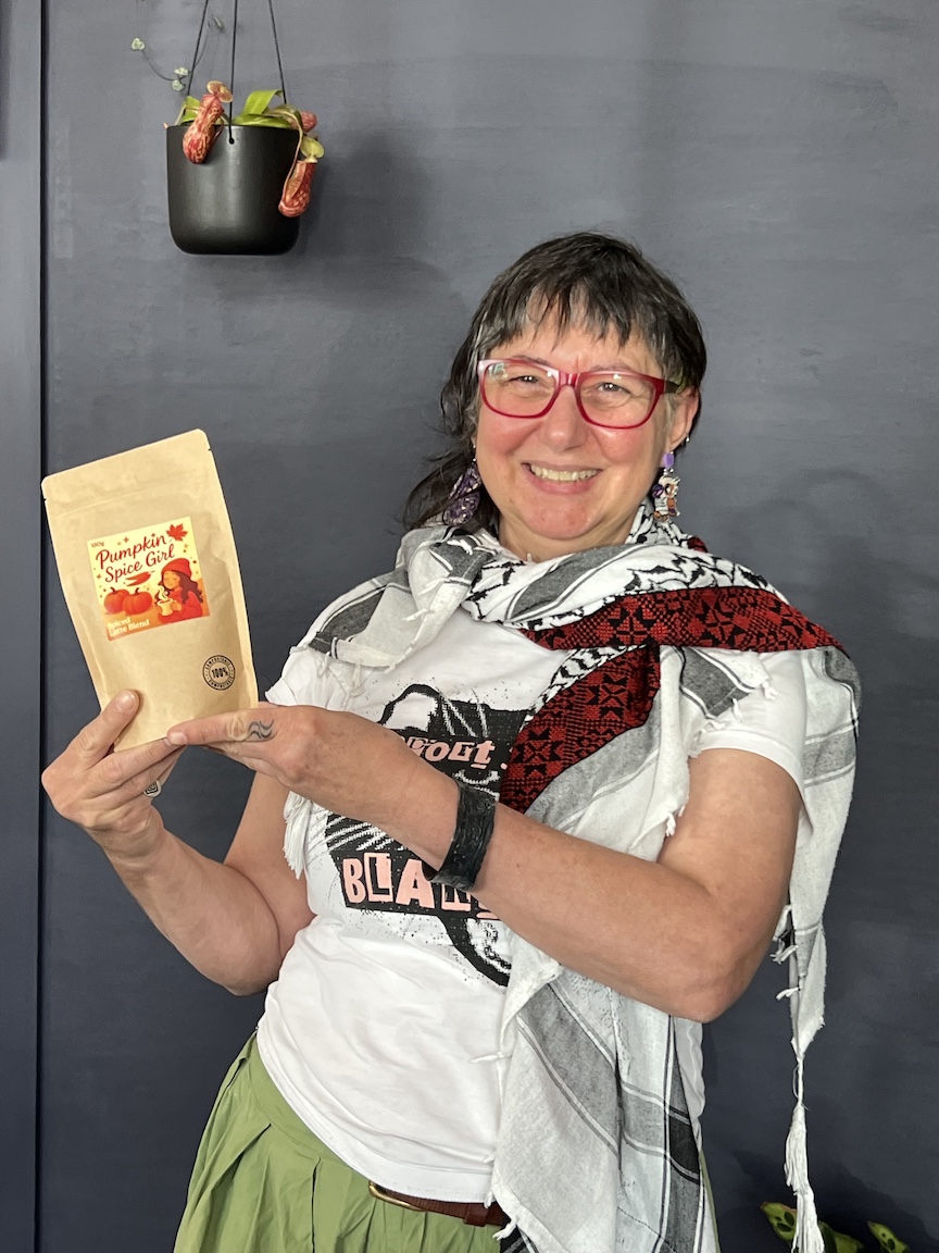 Nada Todorovich, co-founder of Pumpkin Spice Girl, holding up the packaged Pumpkin Spice Girl blend, smiling at the camera.