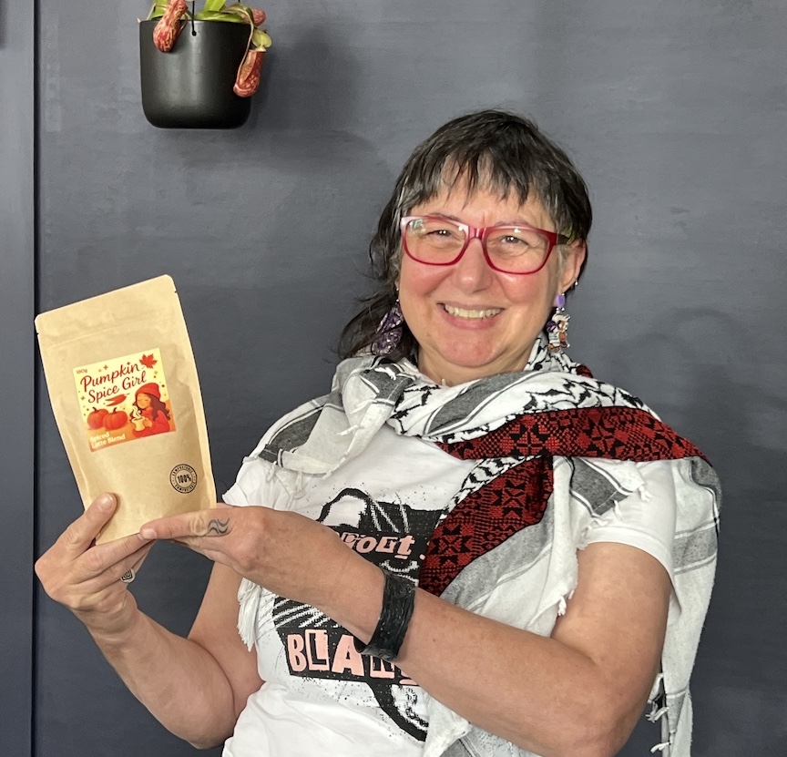 Nada Todorovich, co-founder of Pumpkin Spice Girl, holding up the packaged Pumpkin Spice Girl blend, smiling at the camera.