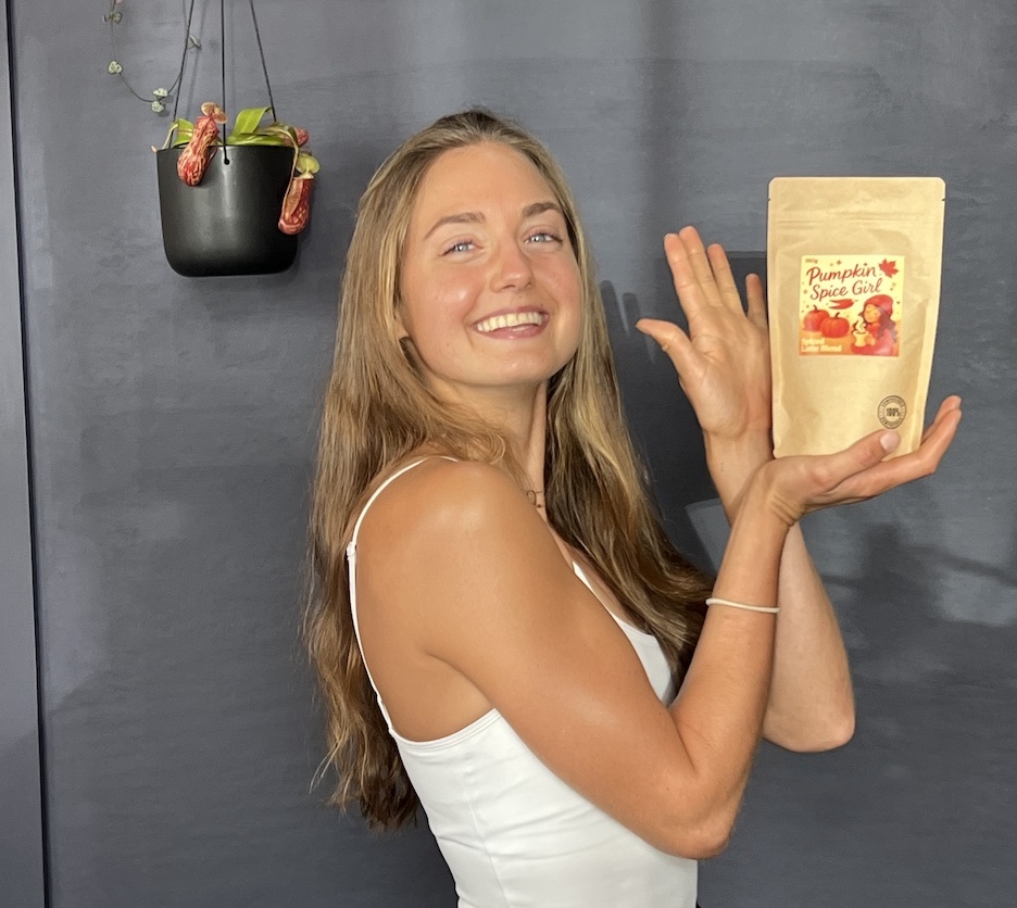 Emilie Meyer, co-founder and producer of Pumpkin Spice Girl, holding up the packaged Pumpkin Spice Girl blend, smiling at the camera.
